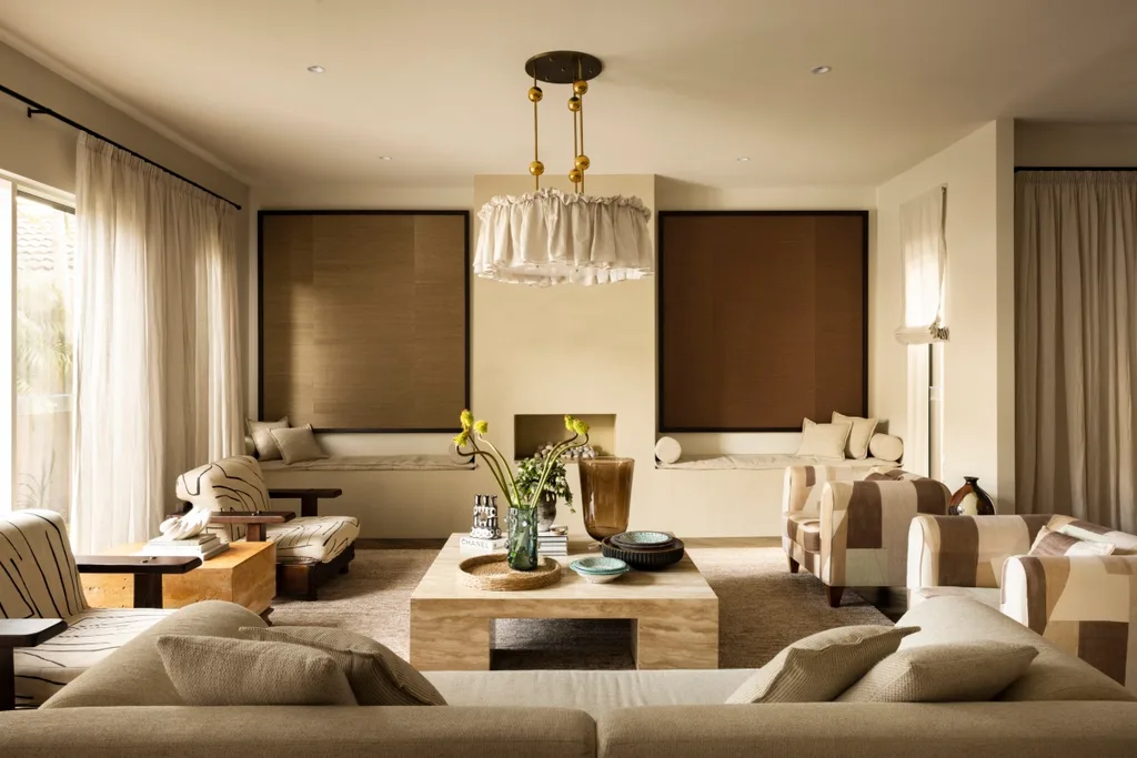 An open plan livig area in warm hues of browns, creams and beige. There is built in seating nooks and a statement pendant lamp.