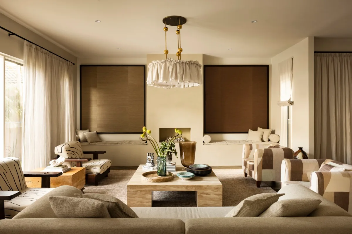 An open plan livig area in warm hues of browns, creams and beige. There is built in seating nooks and a statement pendant lamp. 