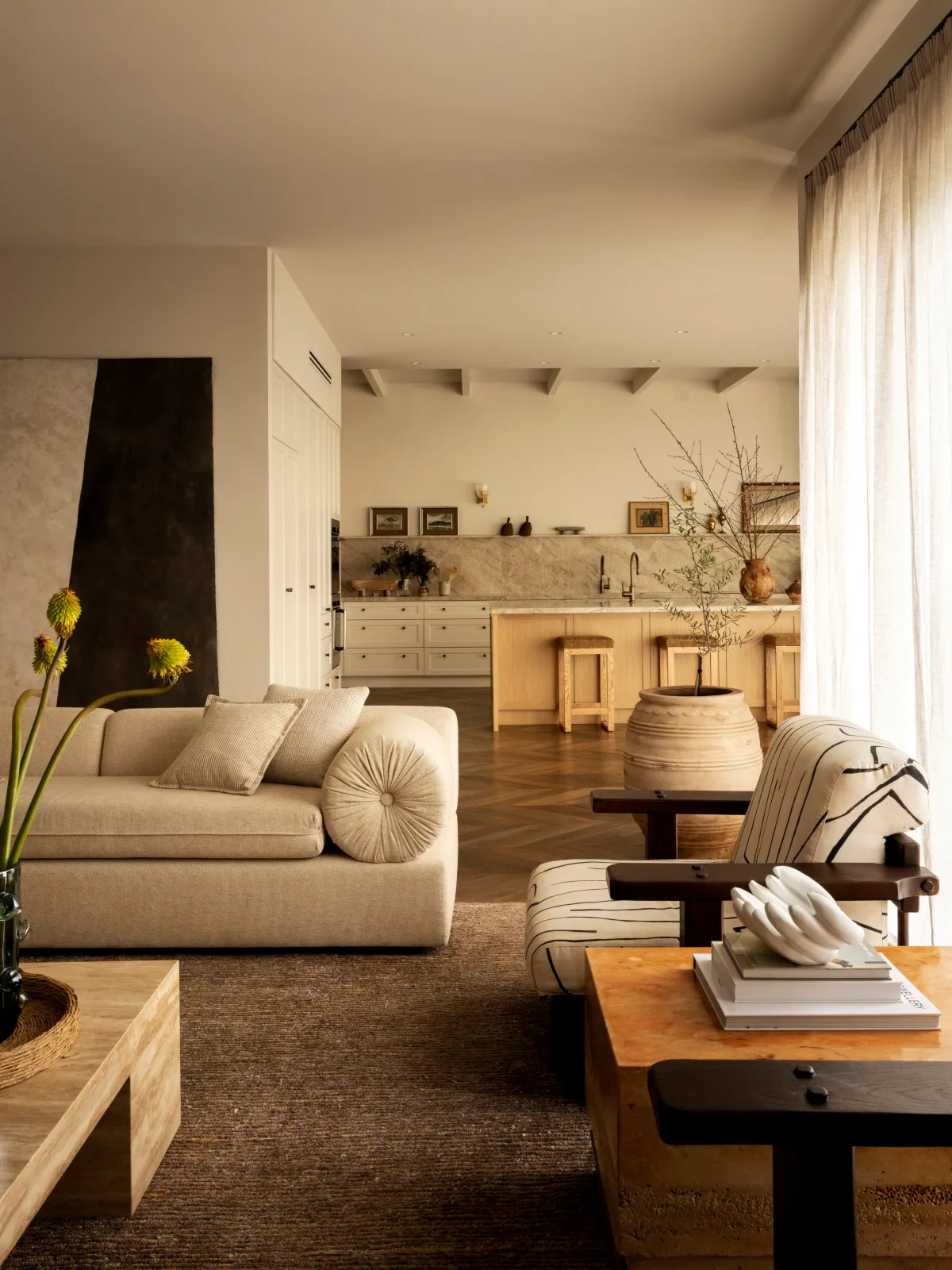 An open-plan kitchen and living space filled with warm colours and soft, natural textures. 