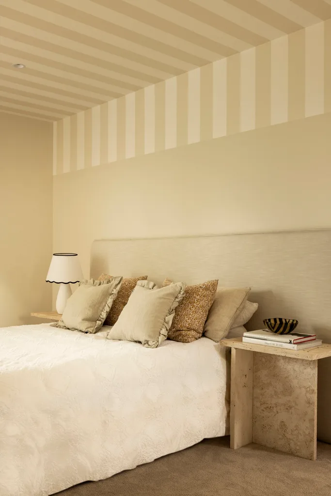 A beige bedroom with a statement striped ceiling.