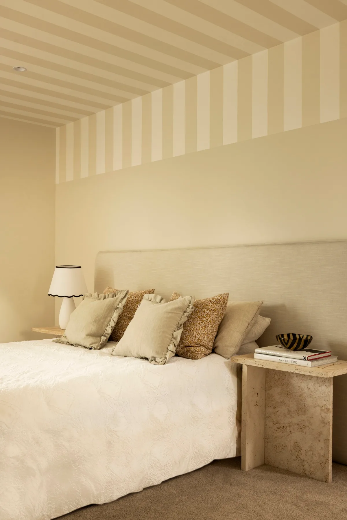 A beige bedroom with a statement striped ceiling. 
