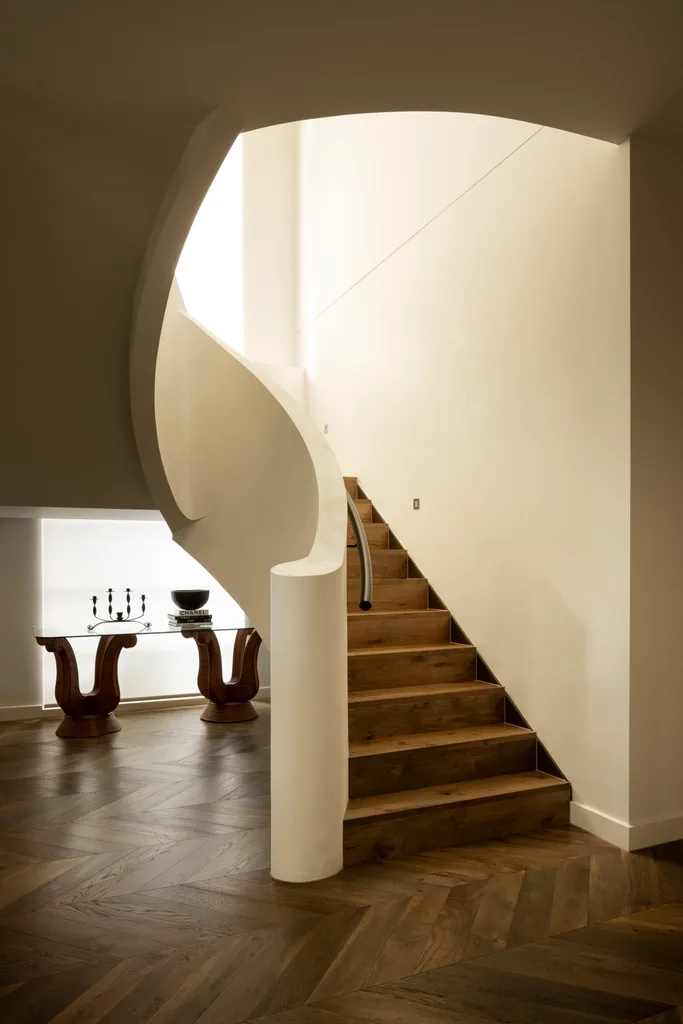 The curved staircase and wood floors inside a warm Melbourne home.