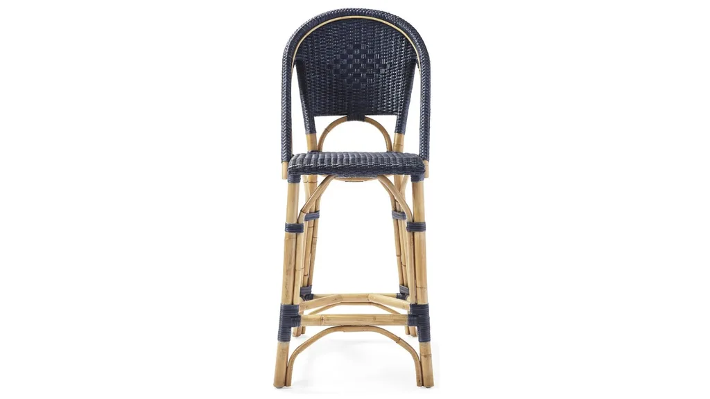 A bar stool with a tall, curved backrest, leg rest and blue rattan material with cane legs.