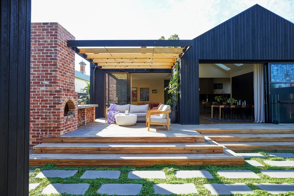 Fleur Harris' home exterior which includes a brick fireplace, alfresco lounge and wooden deck.