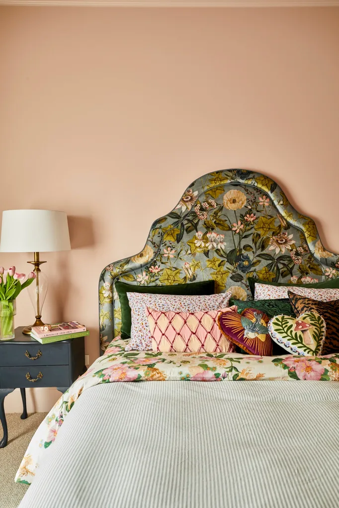 When Fleur Harris worked on her home renovation she painted her main bedroom pink. Her curved bedhead has a predominantly green floral pattern, acting as a contrast alongside a blue bedside table.