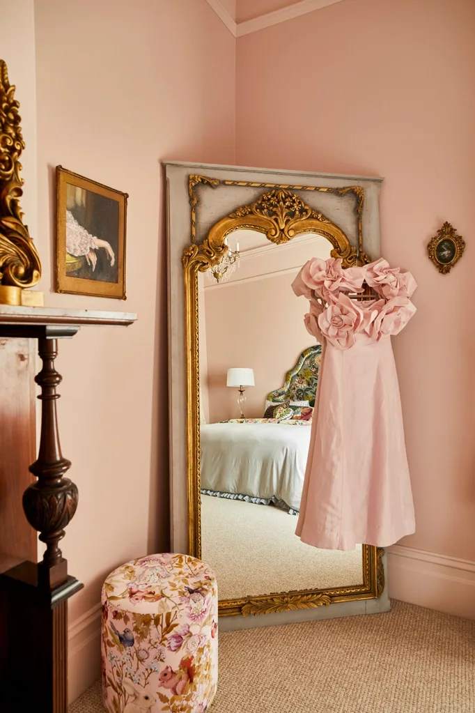 When Fleur Harris worked on her home renovation she painted her main bedroom pink. A pink dress hangs up beside an ornate gold-framed full-length mirror.