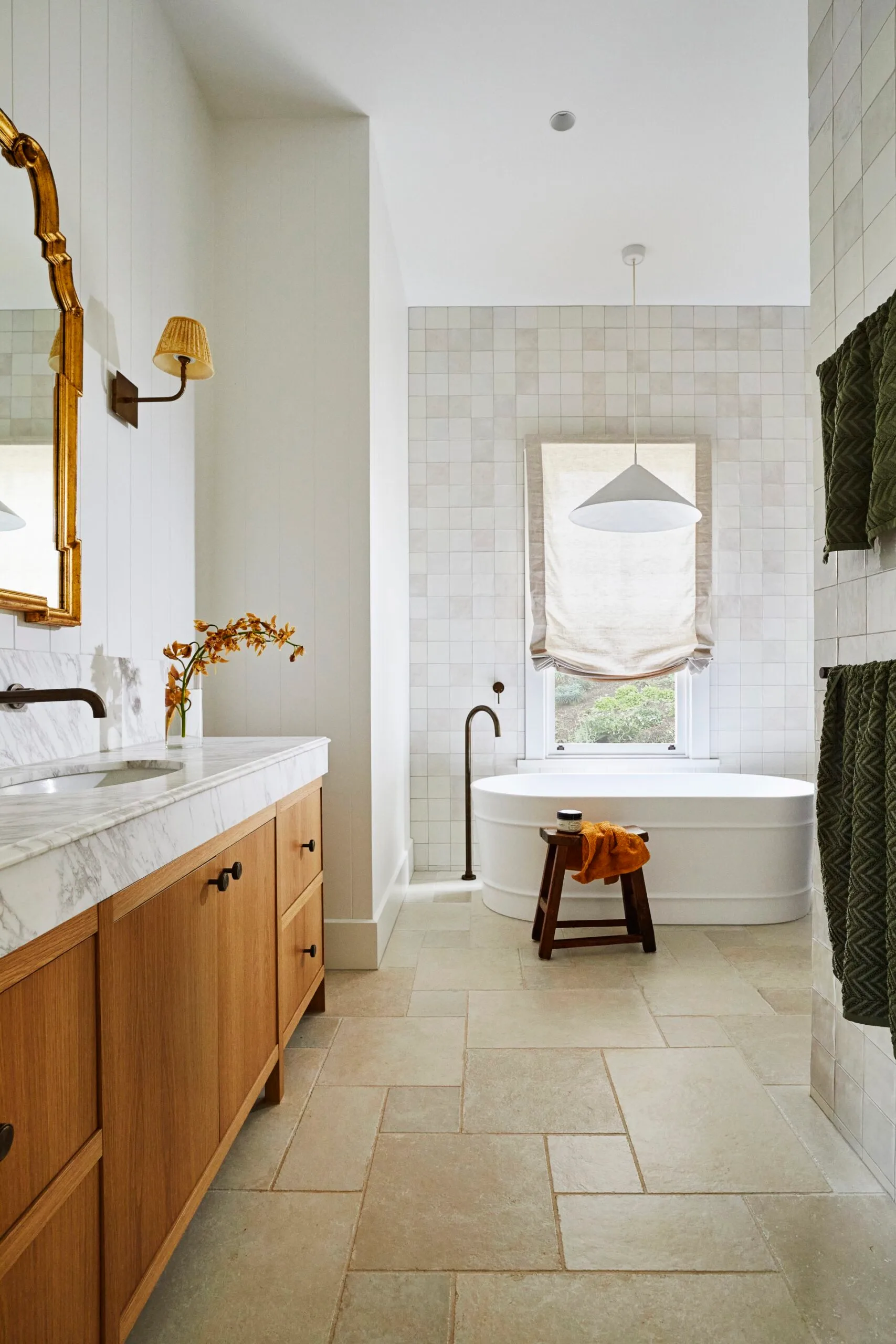A modern farmhouse bathroom with a freestanding bath and timber cabinetry. 