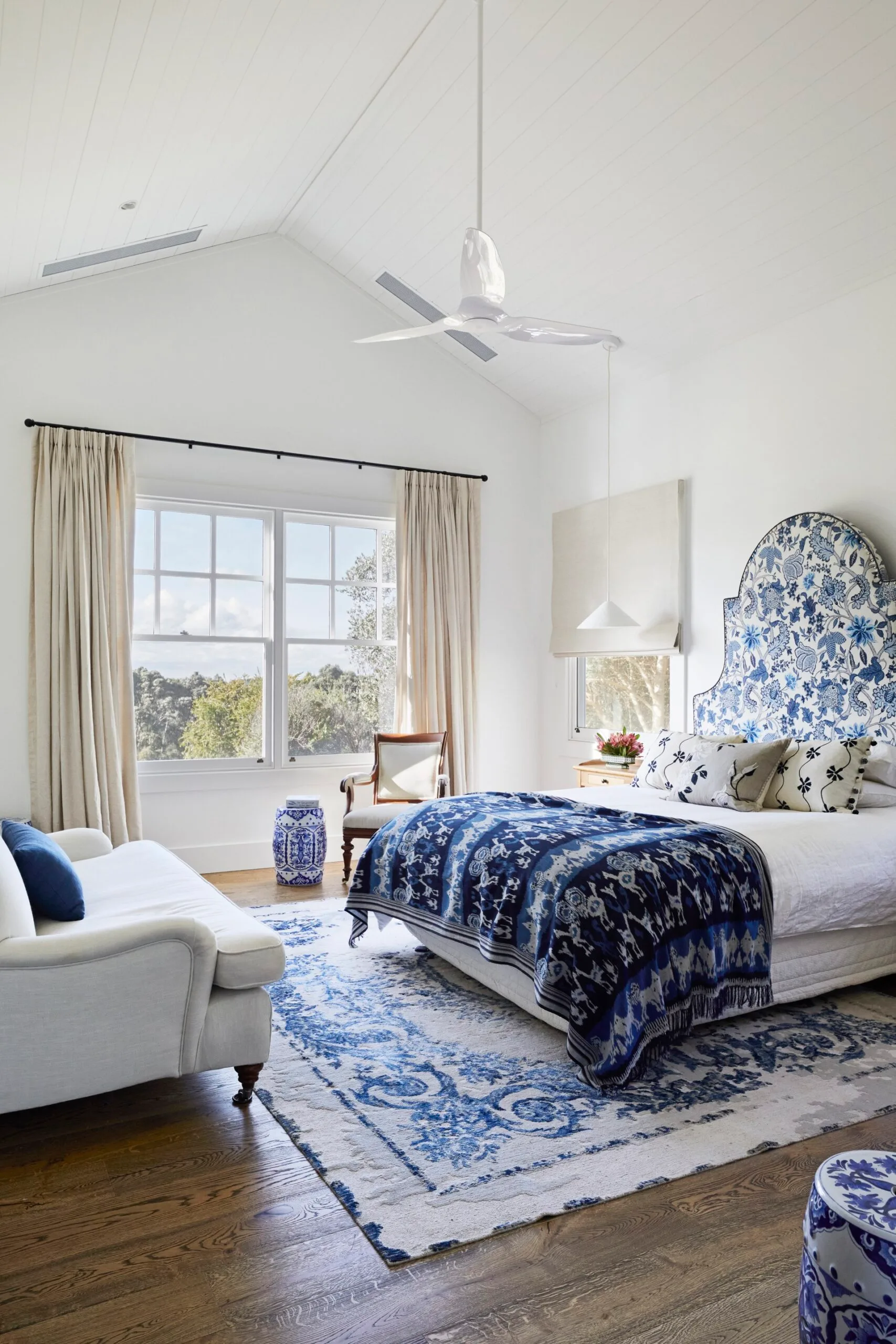 A bedroom inside a modern farmhouse with a blue headboard, quilt and rug. 