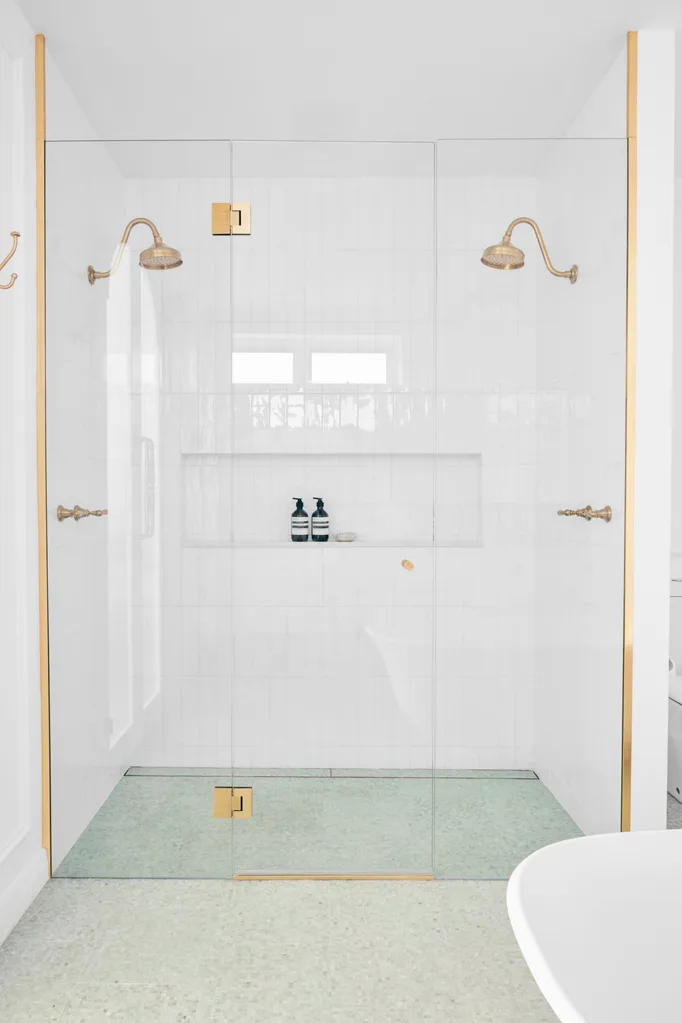 A luxurious double shower with a green mosiac tiled floor.