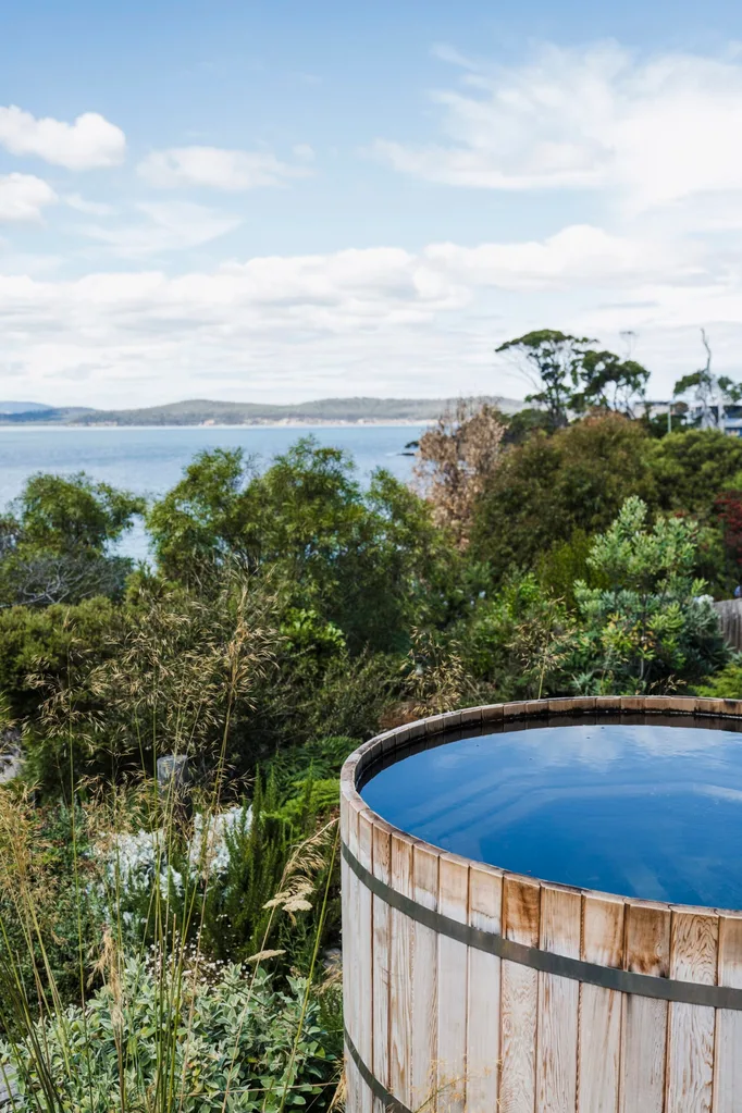 This Tasmanian Airbnb has a round hot tub. Native bushland and sea views are visible from this hot tub.