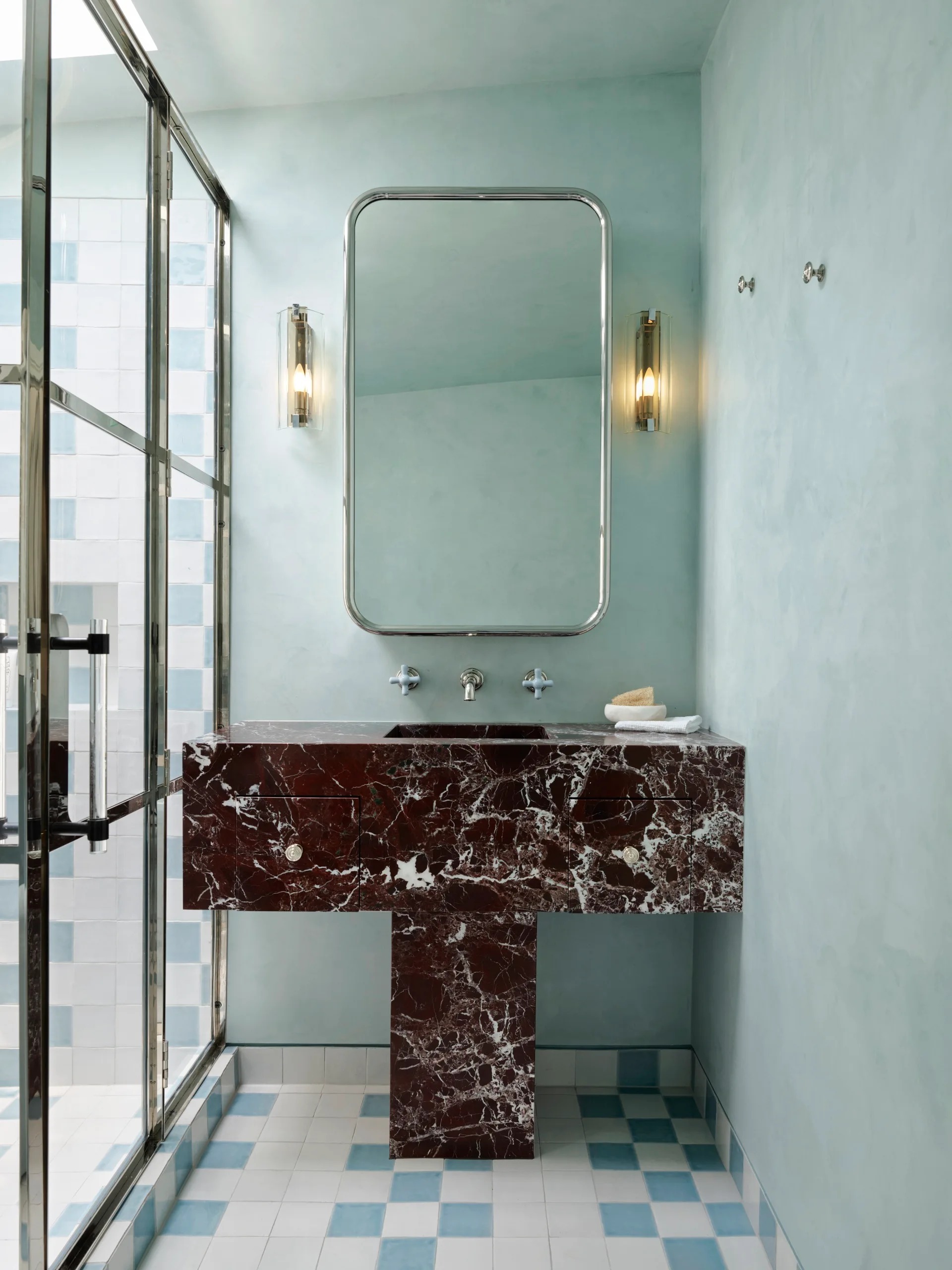 Elegant bathroom with deep red marble sink, large mirror, and blue and white checkered tile floor.