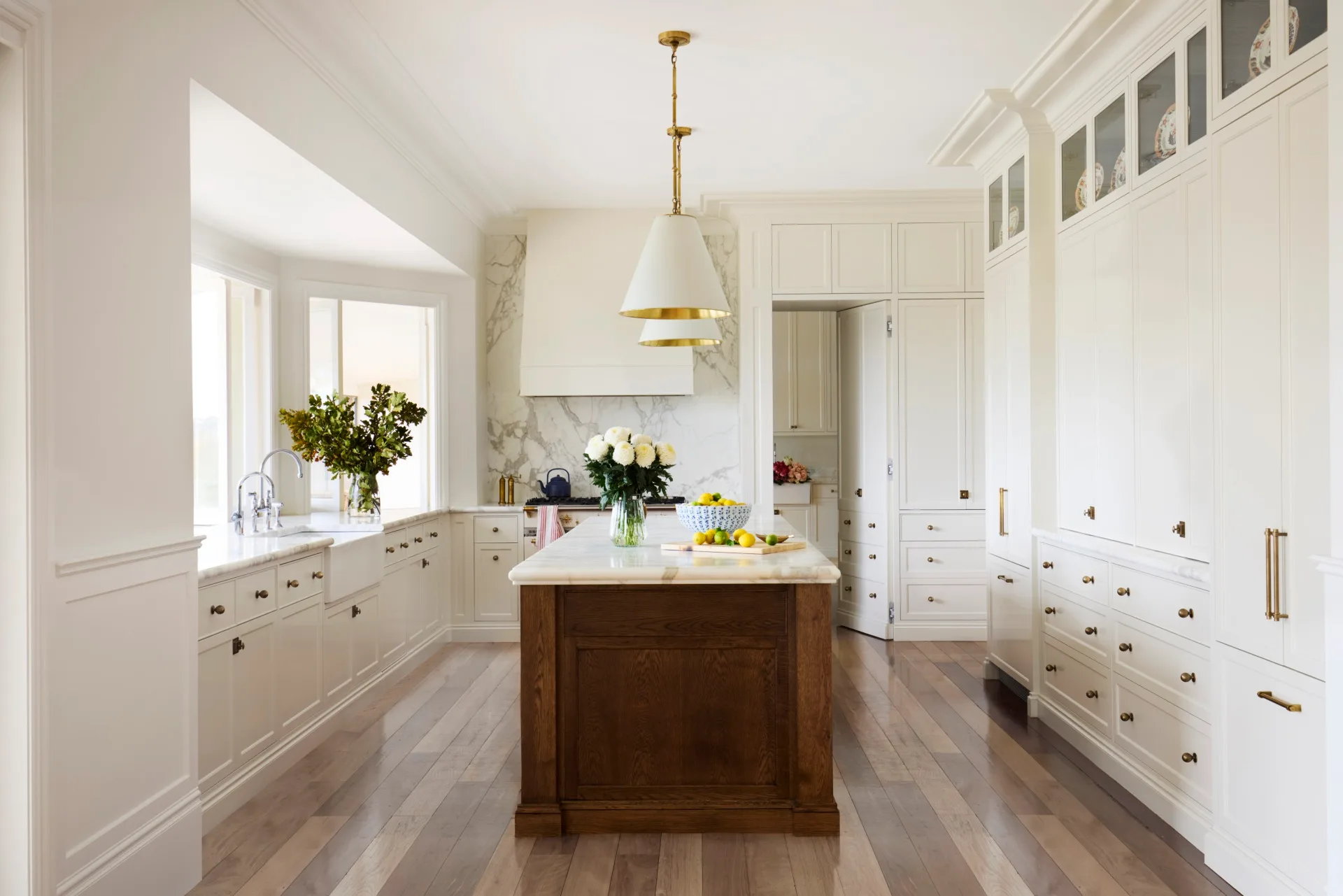 Bright kitchen with white cabinets, wooden island with marble benchtop, and pendant lighting.