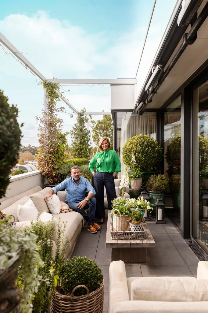 Australian design influencer Chyka Keebaugh and Bryce Keebaugh on the terrace of their penthouse apartment. White couches surround a rectangular wooden coffee table.