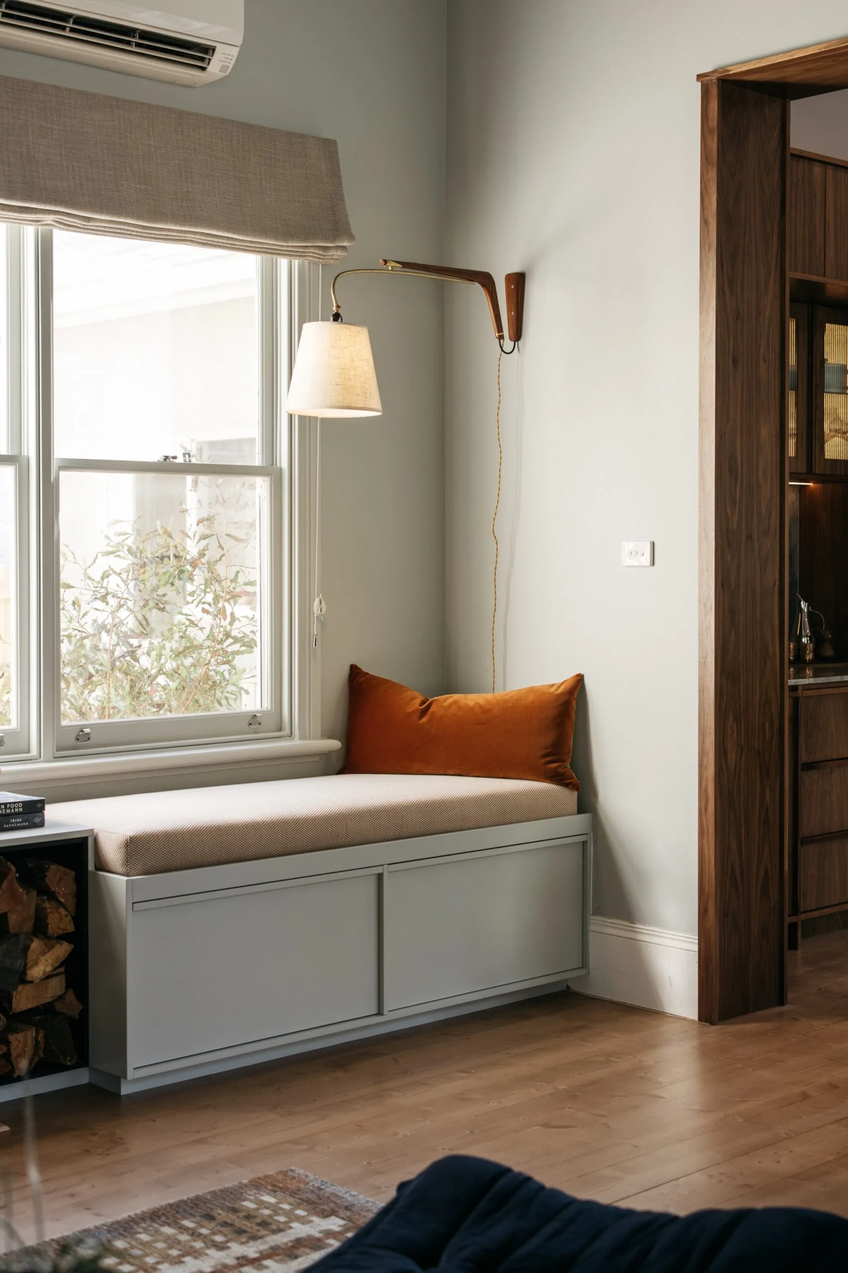 Cosy reading nook featuring a built-in bench, wall light and Roman blinds.