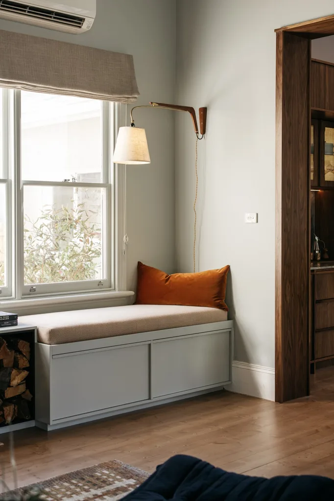 Cosy reading nook featuring a built-in bench, wall light and Roman blinds.