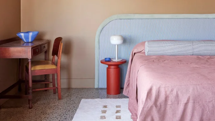Dopamine decor trend featuring a pink bed with an oversized bedhead and red bedside table