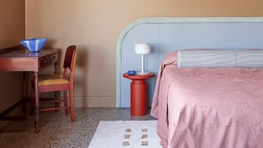 Dopamine decor trend featuring a pink bed with an oversized bedhead and red bedside table