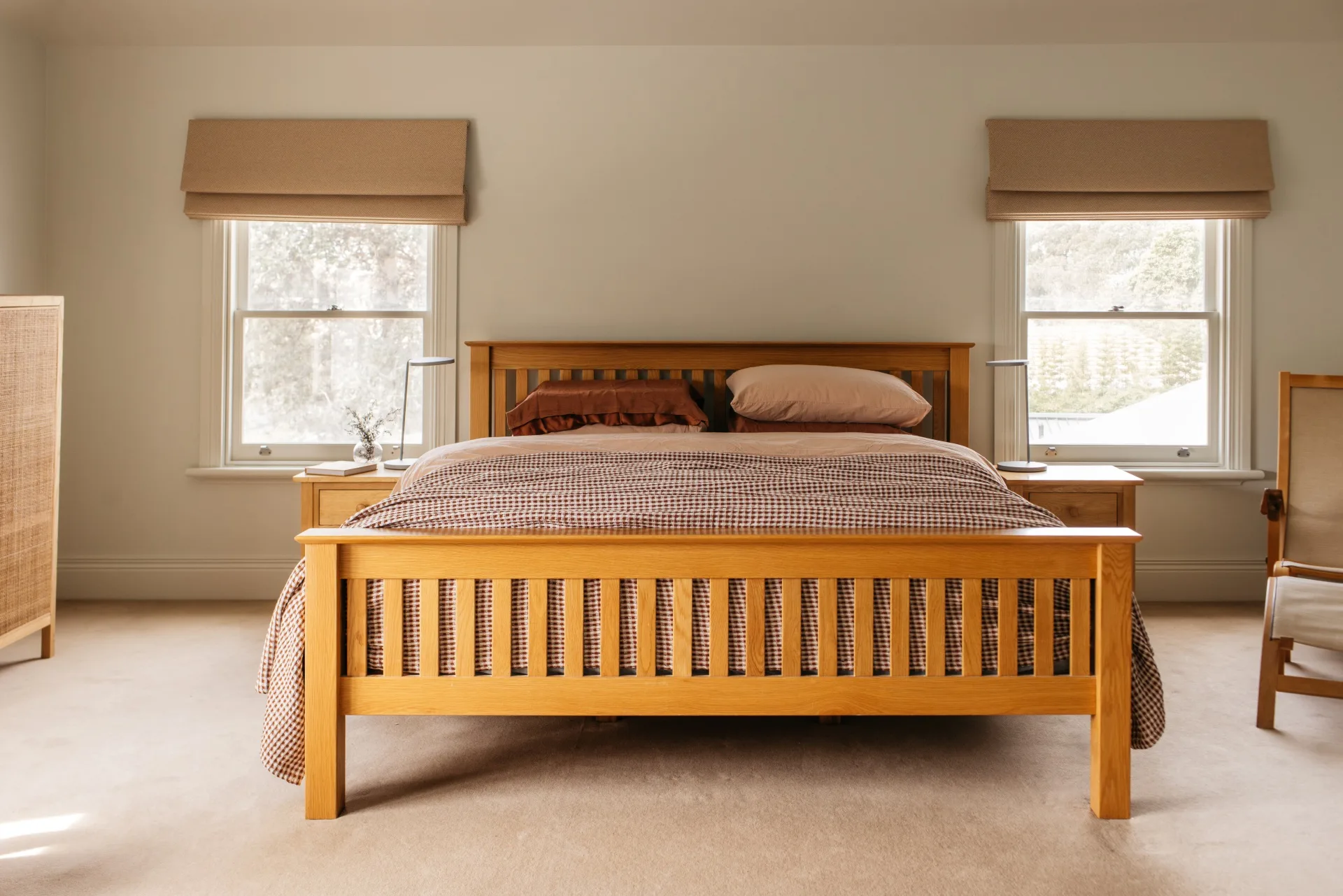 Minimalist main or master bedroom in a heritage home with Scandi-style interiors, featuring a timber bed, Roman blinds and a neutral cream palette.