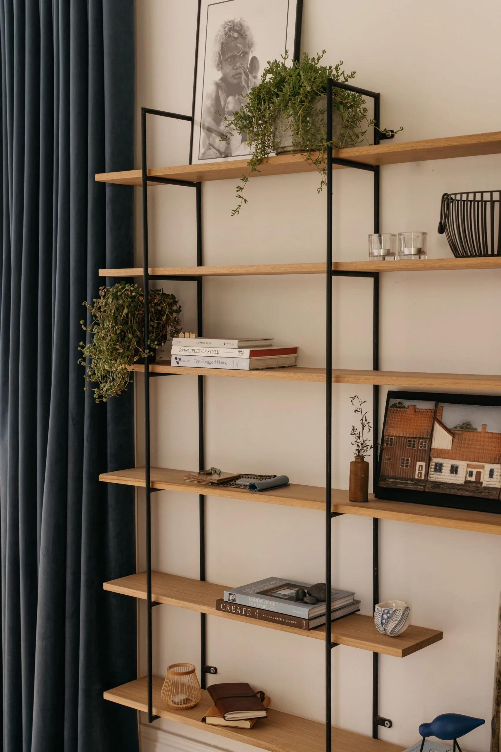 Living room in a heritage home with Scandinavian-style interiors featuring a neutral palette, shelf decor and blue curtains.