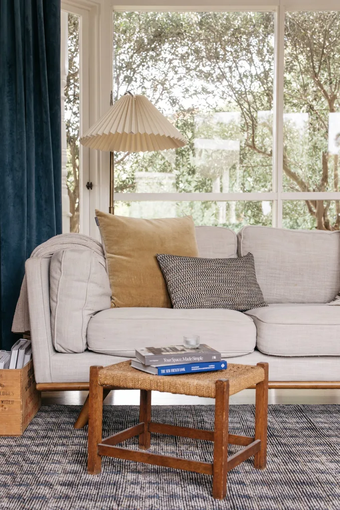 The living room of a heritage home renovated in Scandinavian style featuring a neutral palette, vintage furniture and blue curtains.