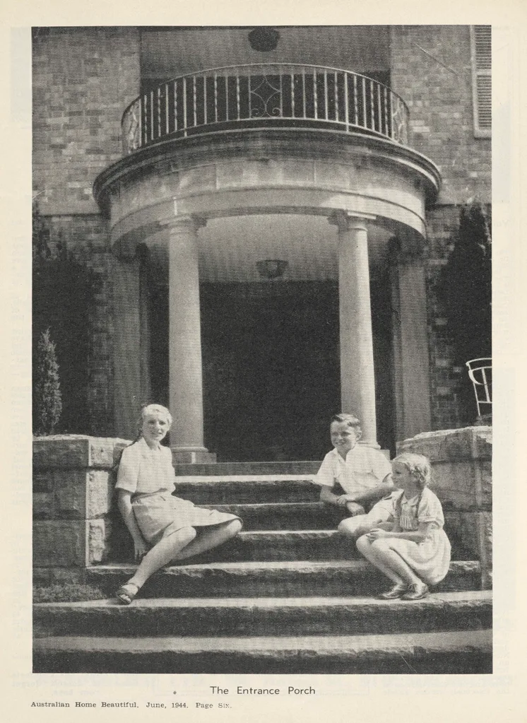 A scanned image of a black and white magazine page. Three children sit on stone steps in front of a large columned porch. Image from Australian Home Beautiful, June 1944