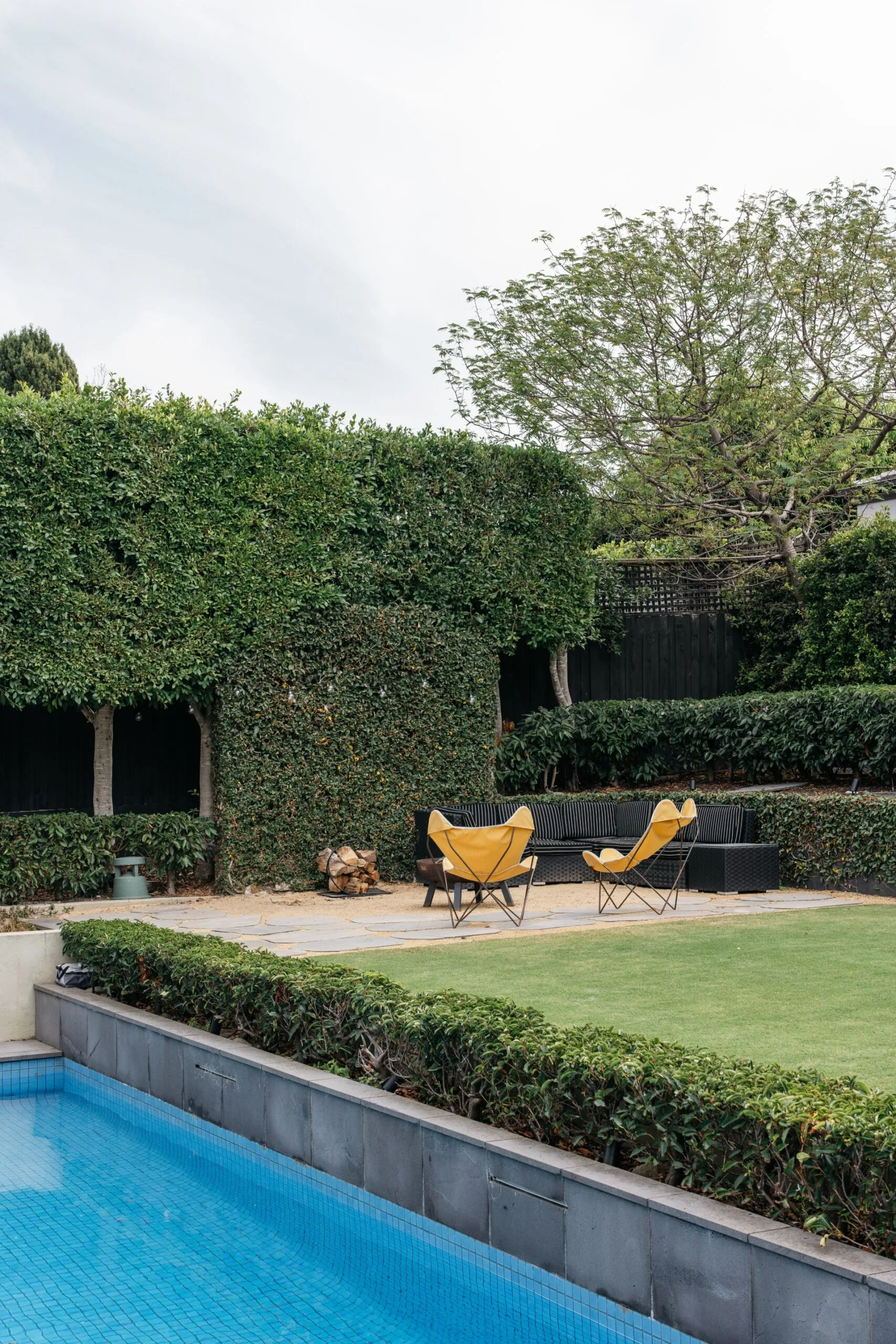 Melbourne Bayside heritage home with a pool, lawn, hedges and butterfly chairs.