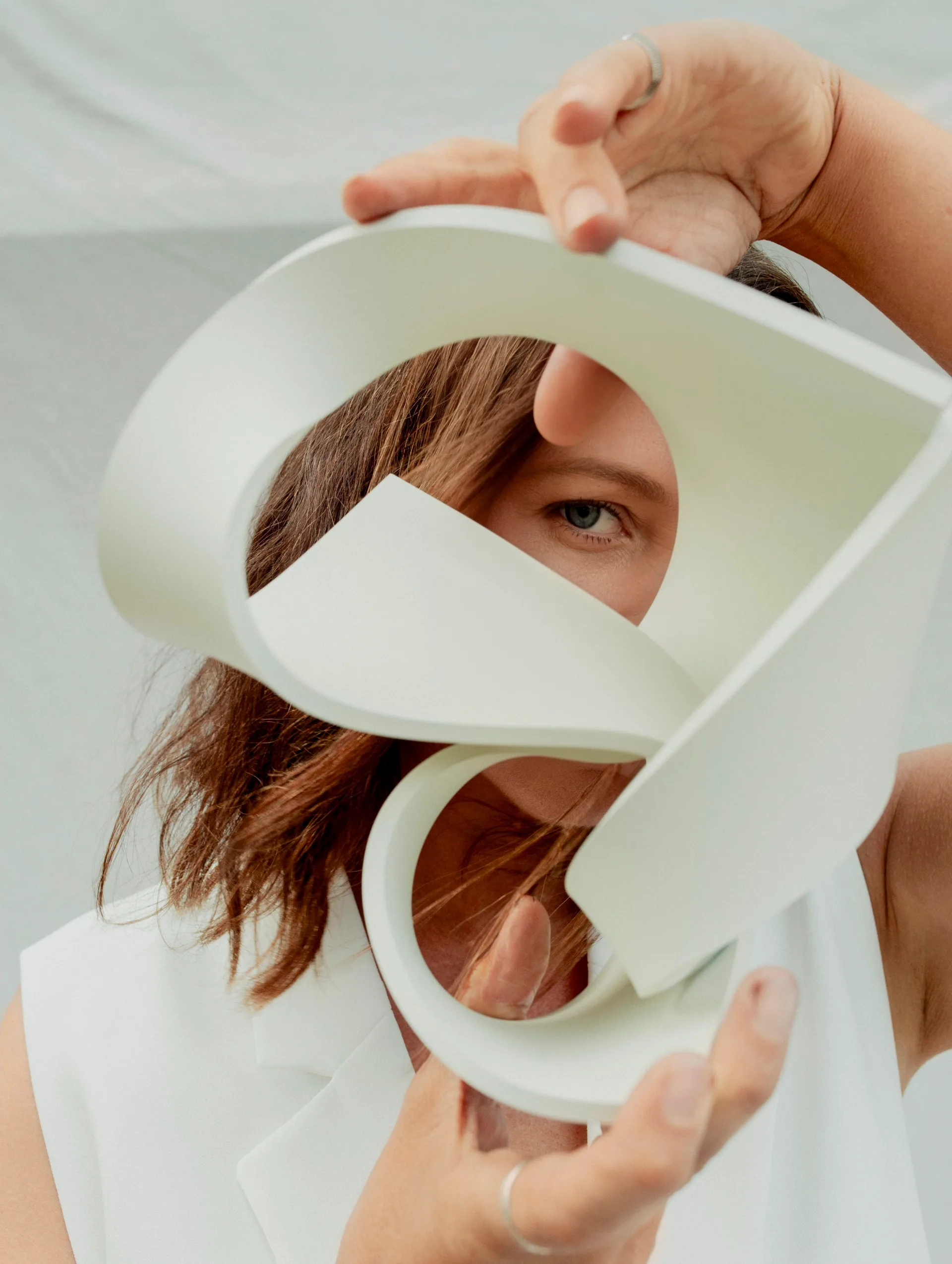 A close up of a woman holding a white polymer sculpture with lots of curved shapes.