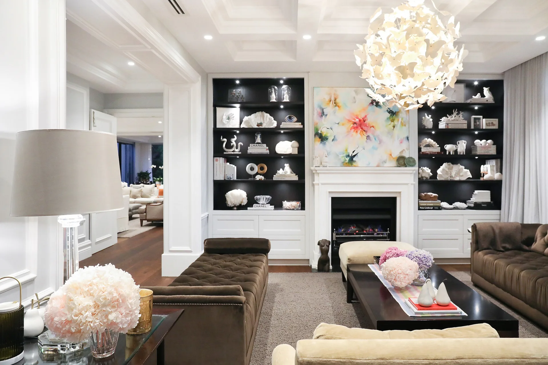 Nicole Gazal O'Neil's formal living room featuring artwork, shelf decor, a fireplace and flowers.