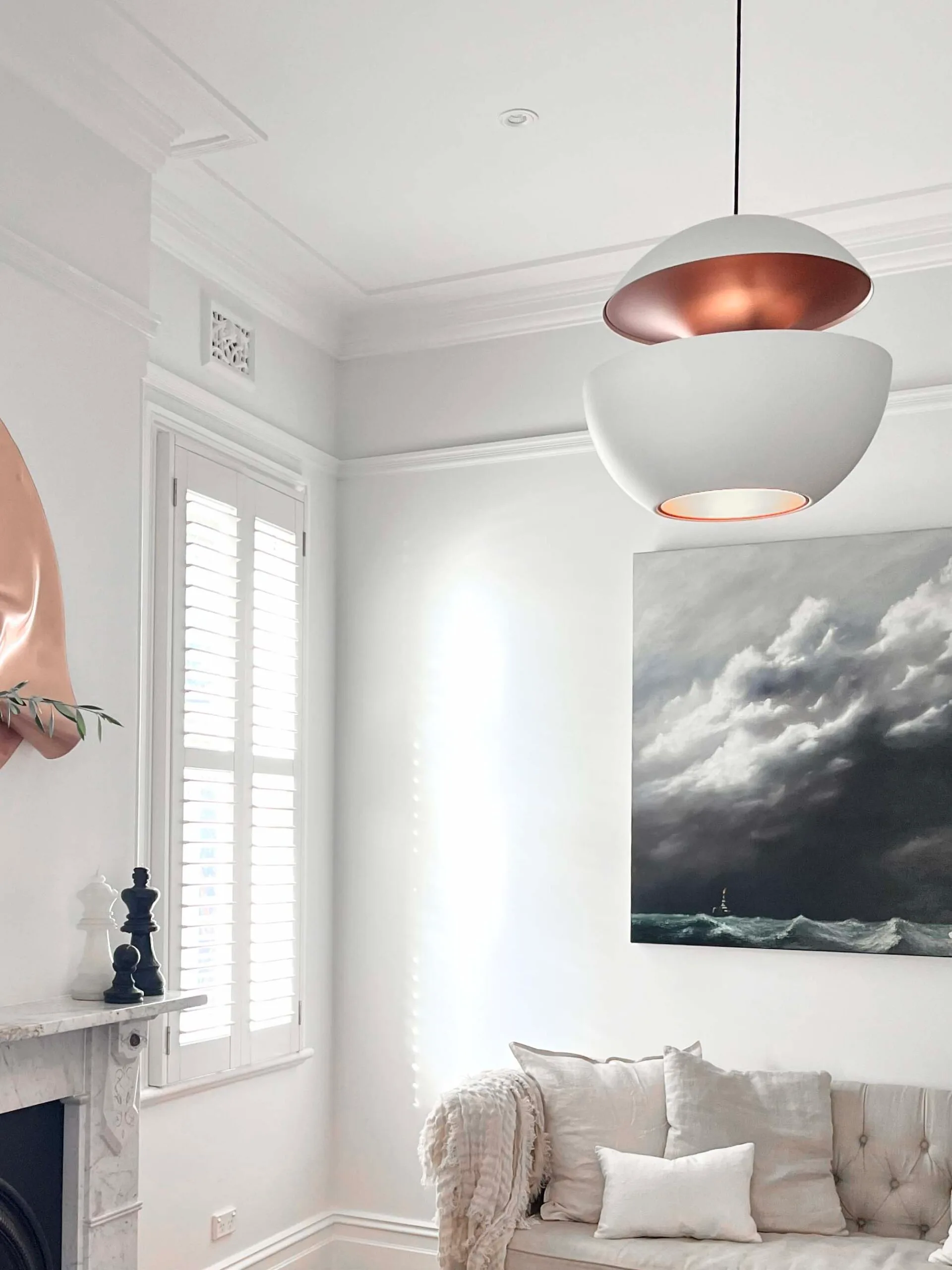 Modern living room with pendant light, tufted sofa, abstract art, and fireplace on a light background.