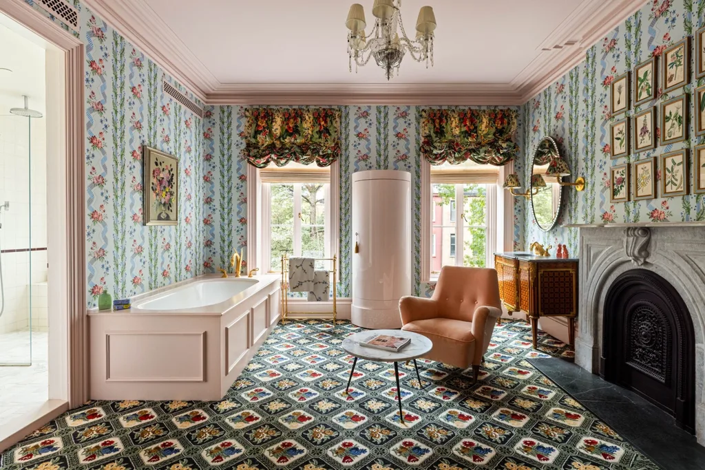 Elegant vintage-style bathroom with floral wallpaper, bathtub, armchair, fireplace, and patterned carpet. The ceiling and bath surrounds are a pale pink.