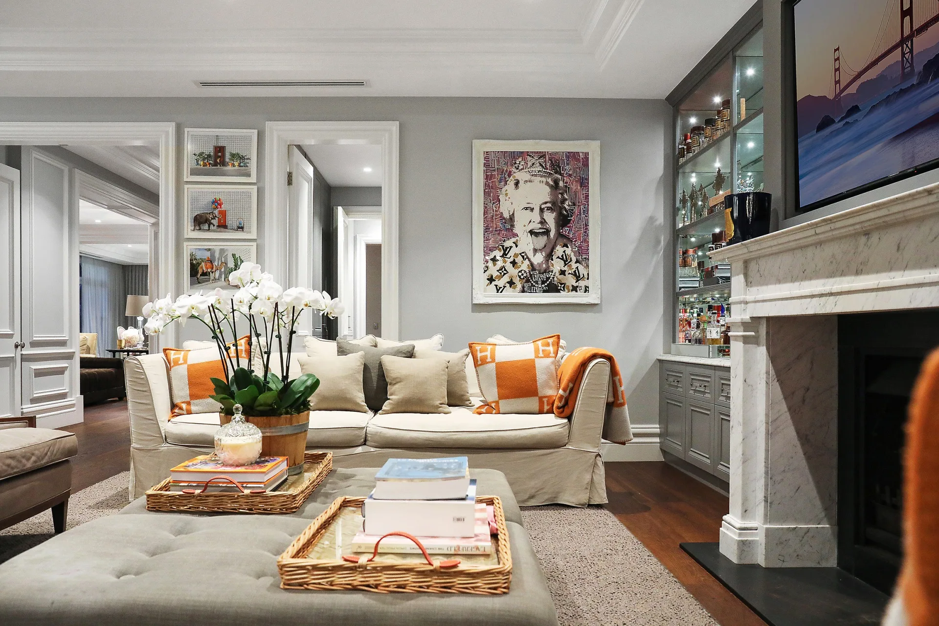 Nicole Gazal O'Neil's family room featuring a beige armchair, sofa and ottoman, and an Hermes cushion, with an artwork by Endless. artwork