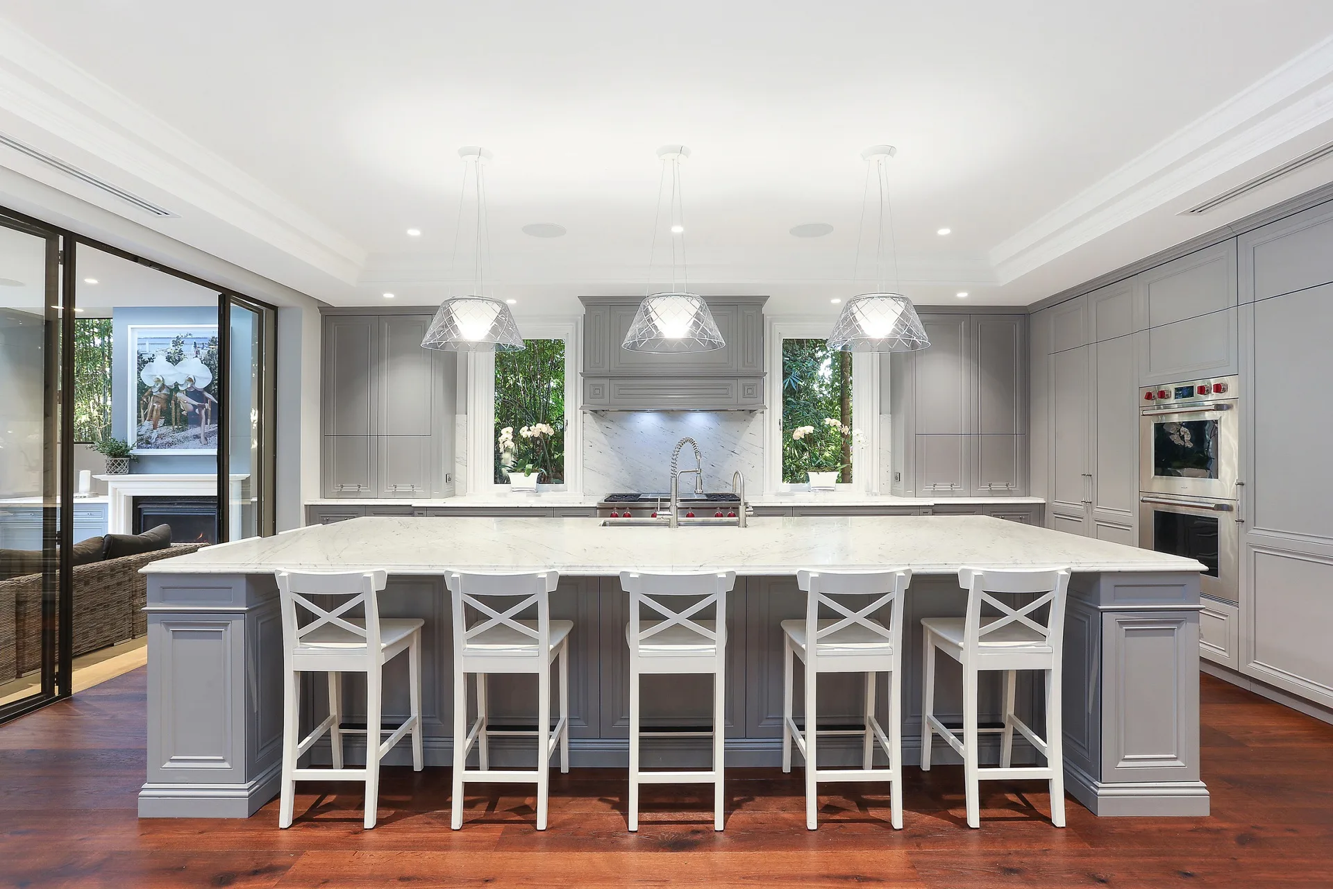 Nicole Gazal O’Neil’s grey Hamptons-style marble kitchen, featuring elegant joinery, a kitchen island bench and white bar stools.