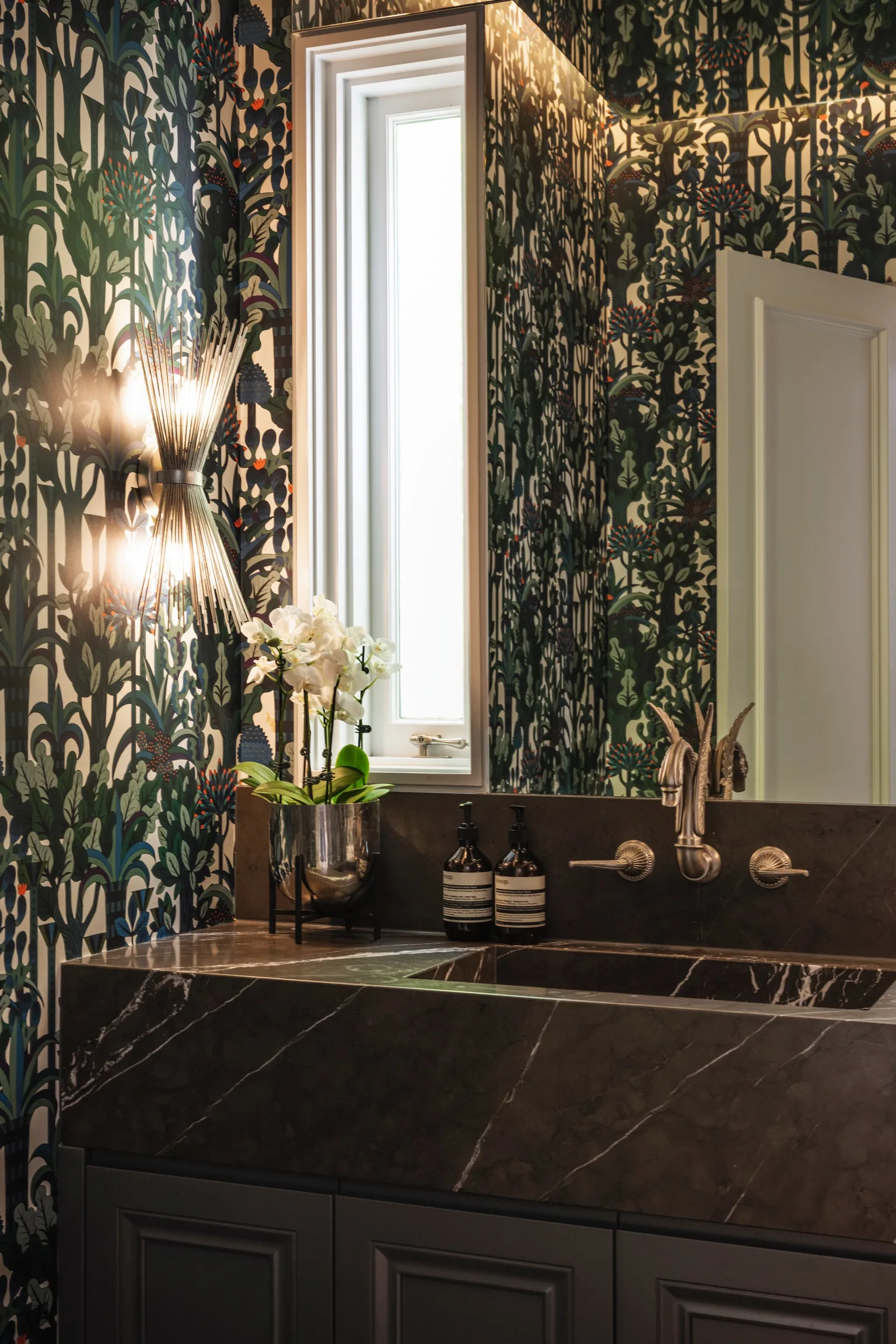 Nicole Gazal O’Neil’s powder room features botanical Hermes wallpaper, blue joinery and a stone vanity benchtop.