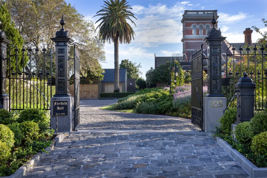 Grand entrance gate to Fairfield Hall, built circa 1892, with landscaped gardens and a historic building visible. The garden was designed by iconic Australian garden designer Paul Bangay.