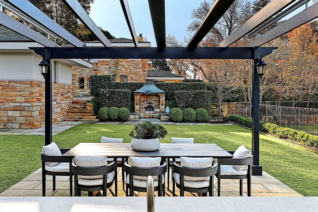 Outdoor dining area in the backyard of a Walter Burley Griffin house in Pymble with a lawn and arbor.