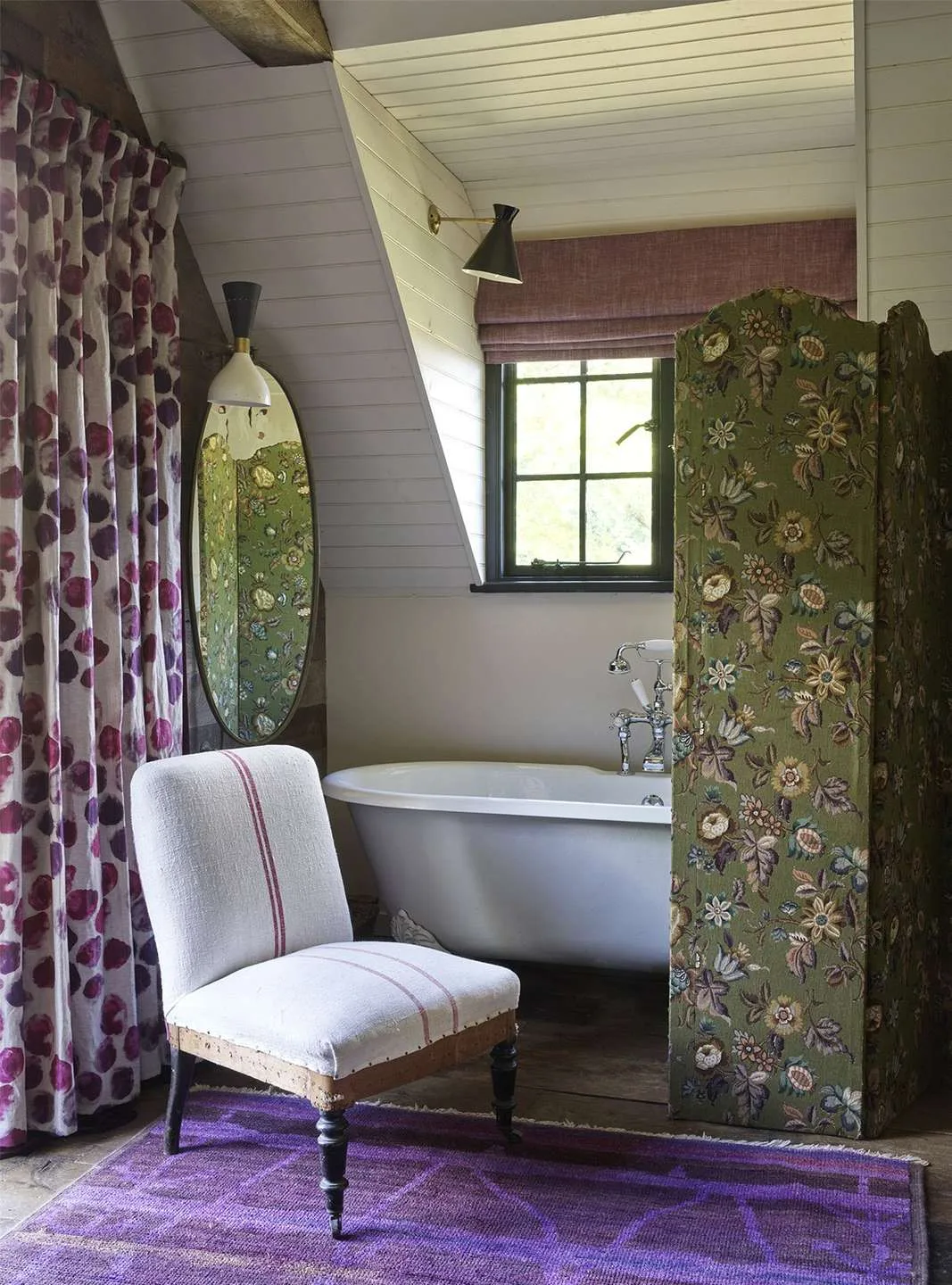 Sienna Miller's bedroom featuring a free standing claw foot bathtub, mirror, armchair and partition