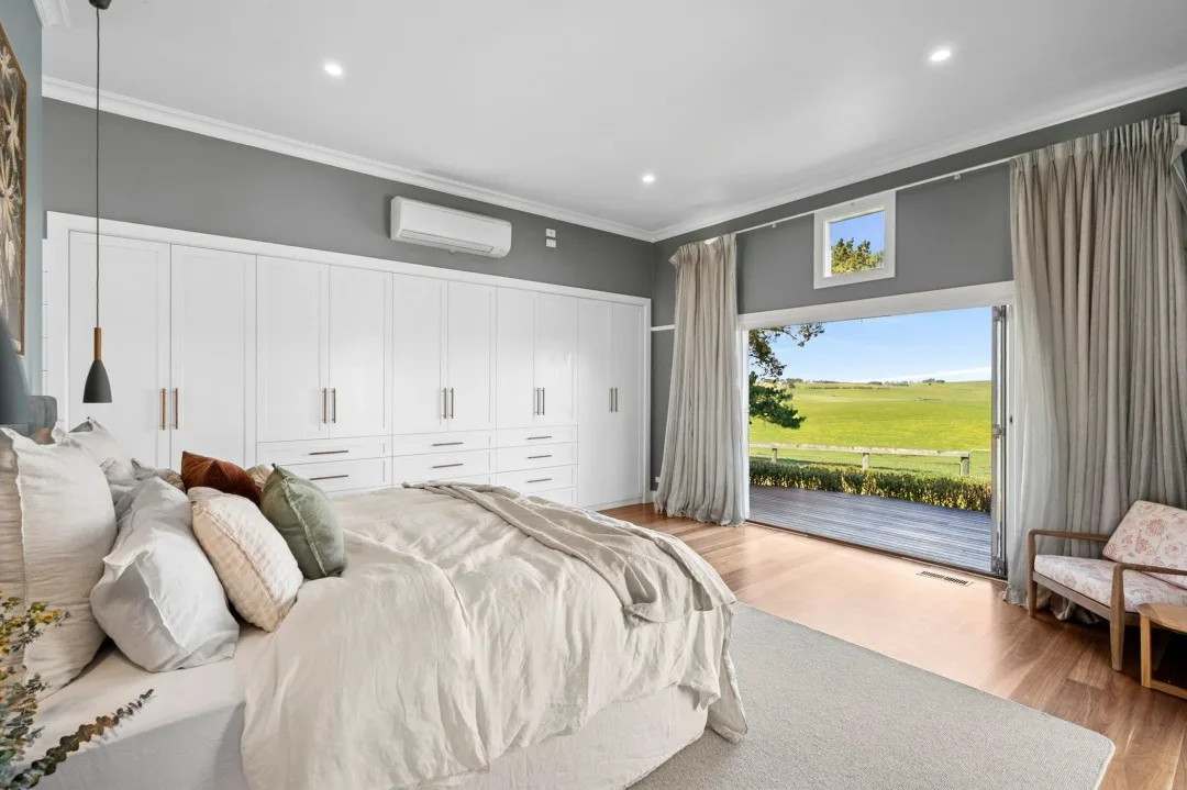 Picture window, grey walls and white wardrobes in Tom and Emma Hawkins' main bedroom.