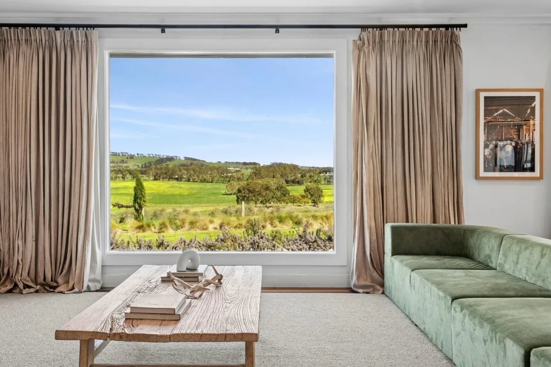 Views of Tom and Emma Hawkins' farm from a large picture window in the family room, which features a green RJ Living sofa and coastal coffee table.