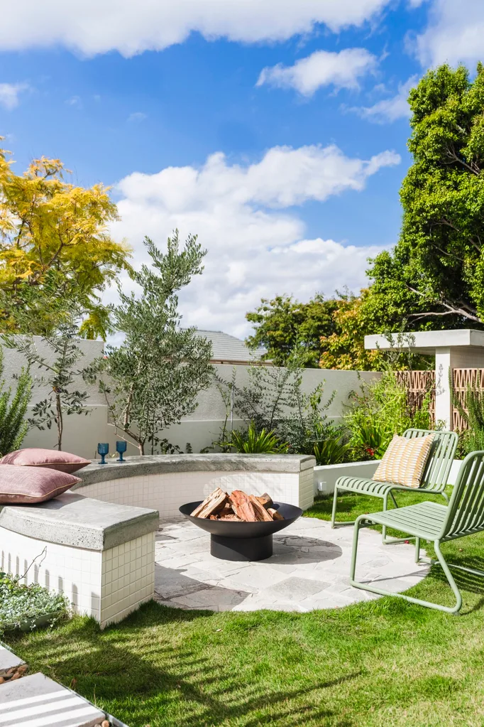 Fire pit in a backyard with green outdoor chairs.