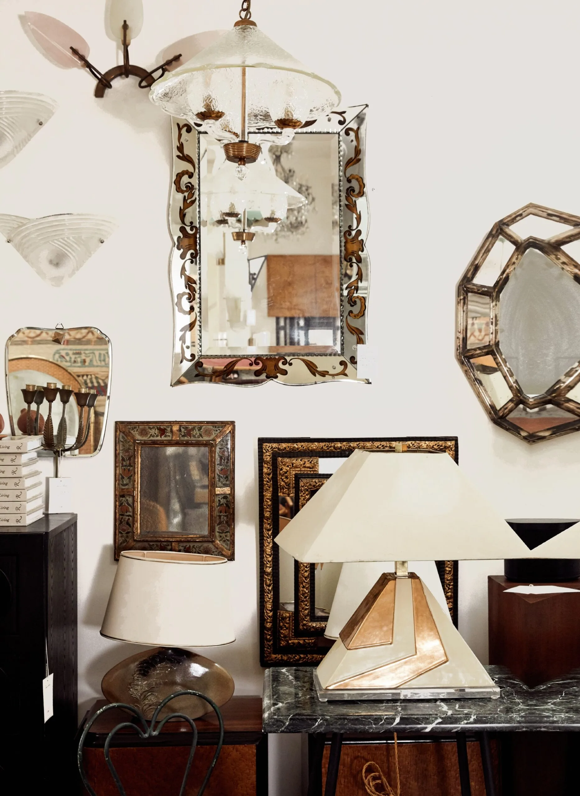 Antique shop with decorative mirrors, lamps, and wall sconces displayed on a white wall