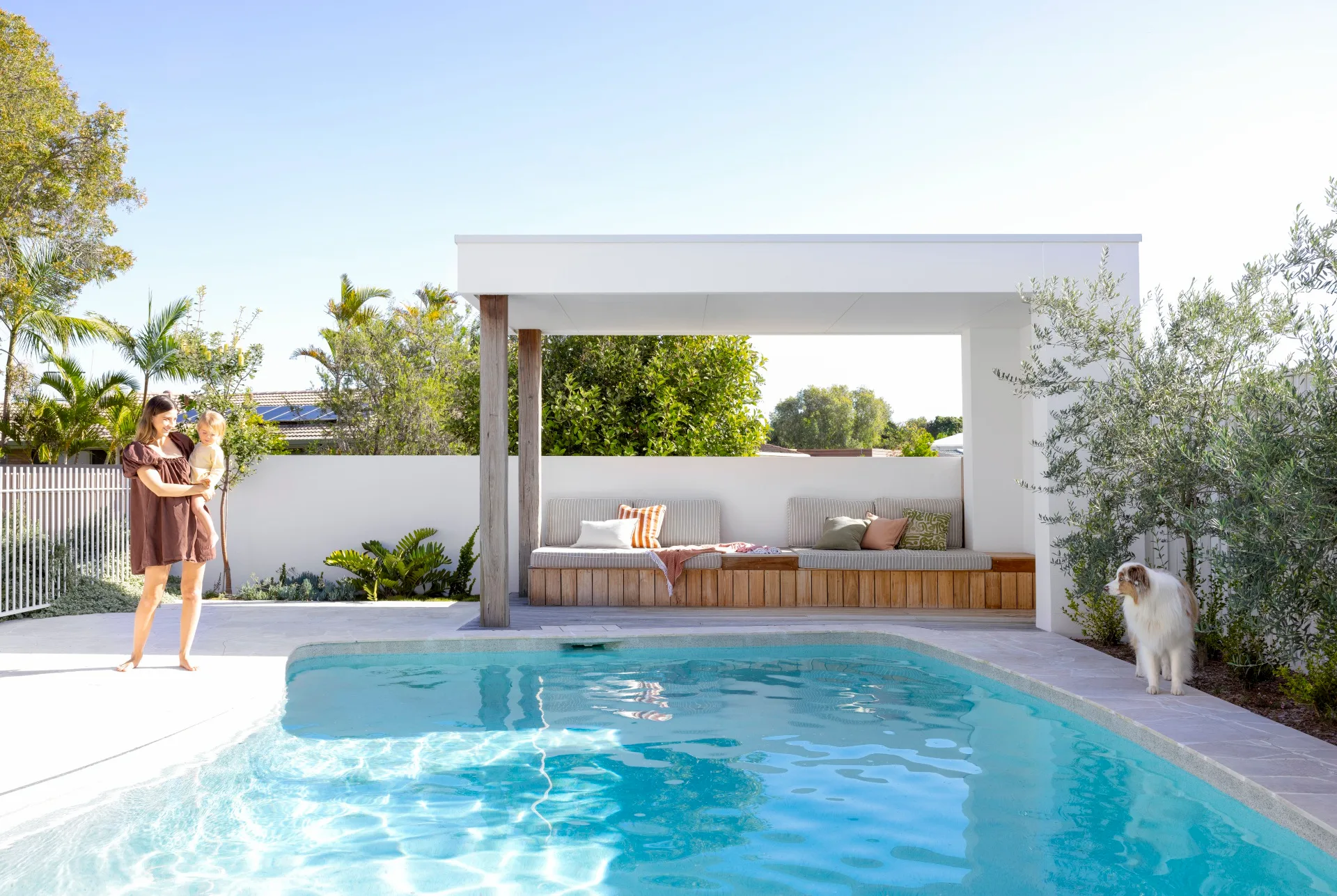 Pool and cabana with built-in bench seating; image features a mother and baby, and a dog.