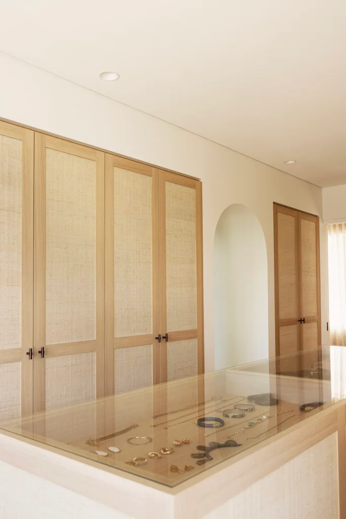 Walk-in robe in a coastal Sydney Mediterranean-style house featuring rattan cupboard doors and a jewellery display cabinet.