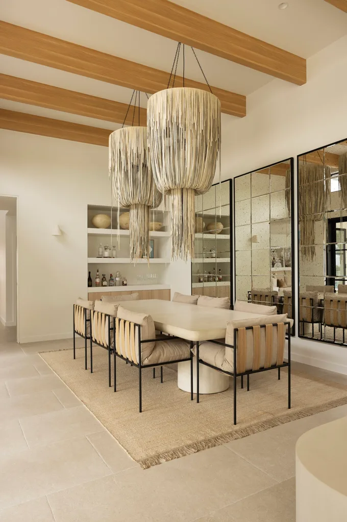 Formal dining room in a coastal Sydney house with a neutral, beige Mediterranean aesthetic featuring leather Balinese pendant lights and rustic mirrors.