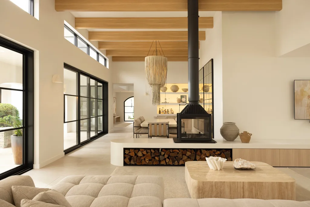 Living and dining room of Sydney coastal house with a Mediterranean aesthetic, featuring a wood fireplace.
