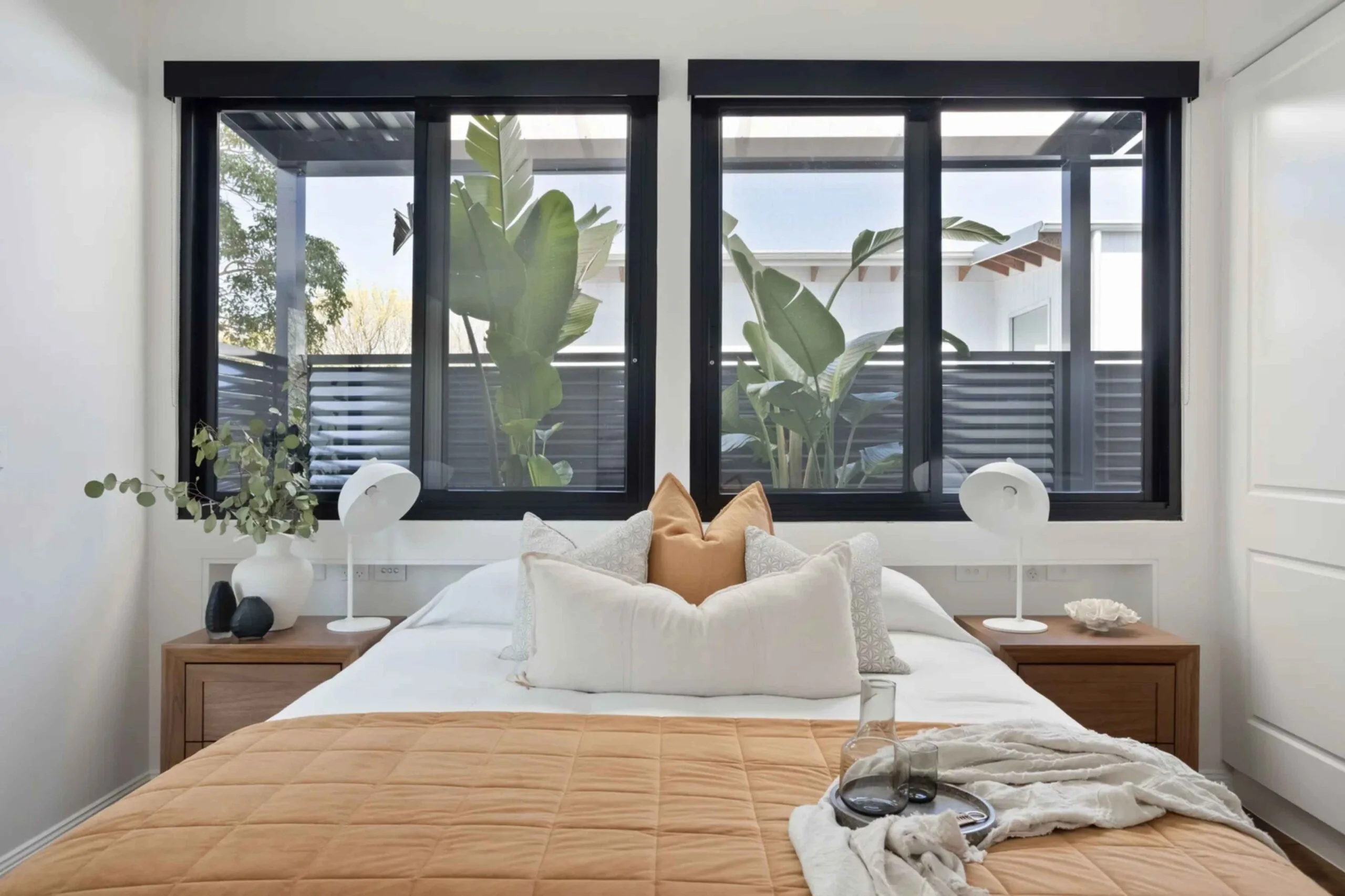 Contemporary main bedroom with black window frames and decor with an earthy palette.