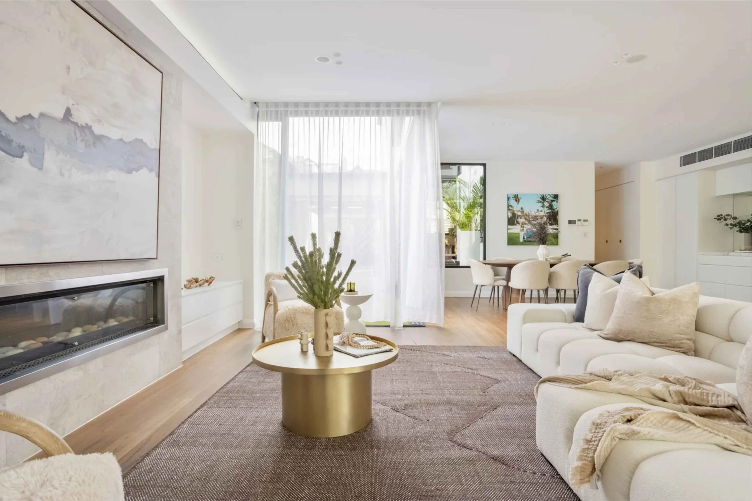 Family room or casual living room in the extension of a Victorian-era house in Sydney, with white furniture, a fireplace, artwork and a mauve rug.