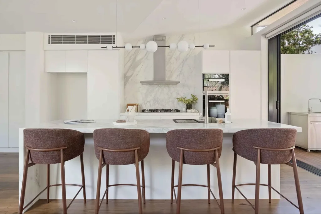 White and marble kitchen with brown bar stools.