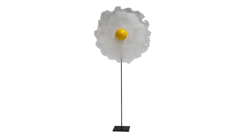 Table lamp on a thin stand with a small yellow sphere on a wide, flat round white surface. The design is reminiscent of a cracked egg.