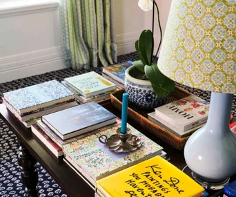 Books, lamp and candle holder on a coffee table in a home decorated by interior designer Anna Spiro.