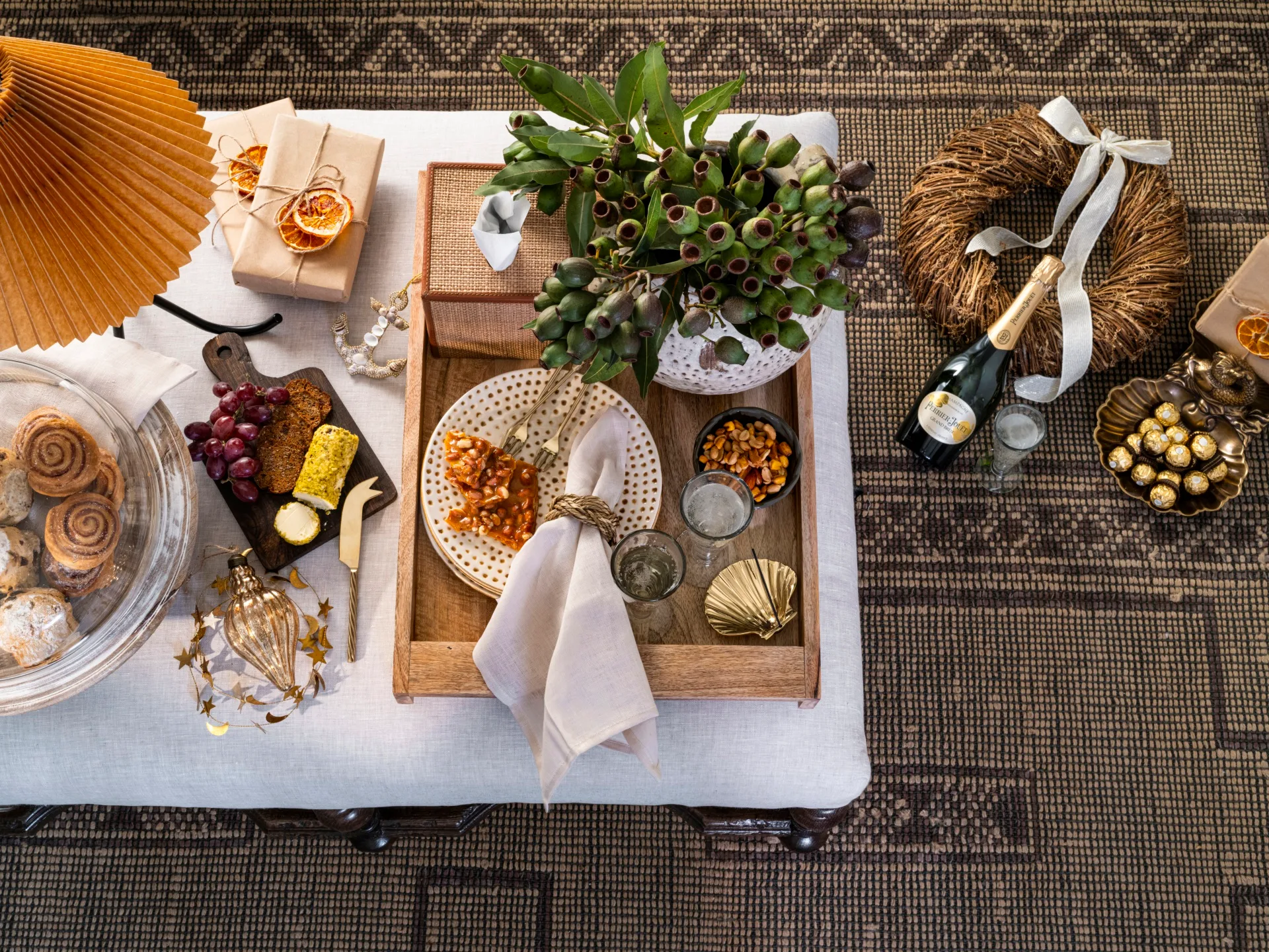 Festive ottoman styled and decorated in an Australian nature-inspired theme with champagne, a cheese board and a wreath.